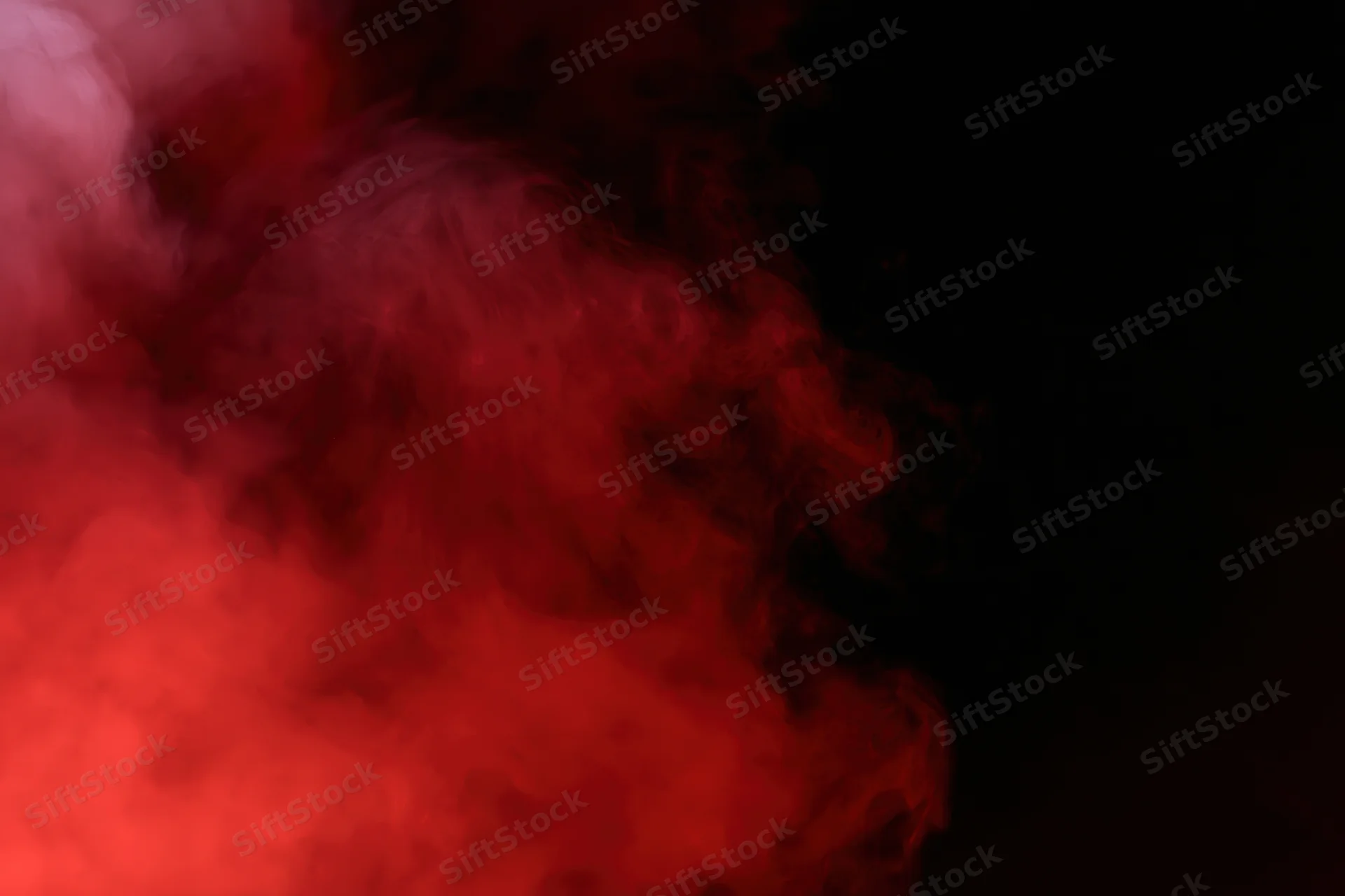 Swirling red smoke illuminated by a single gel light against a dark background