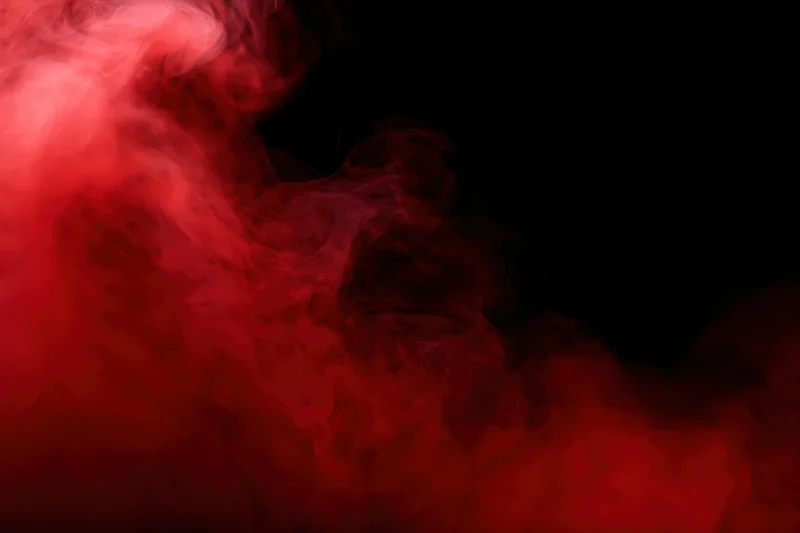 Swirling red smoke illuminated against a dark background