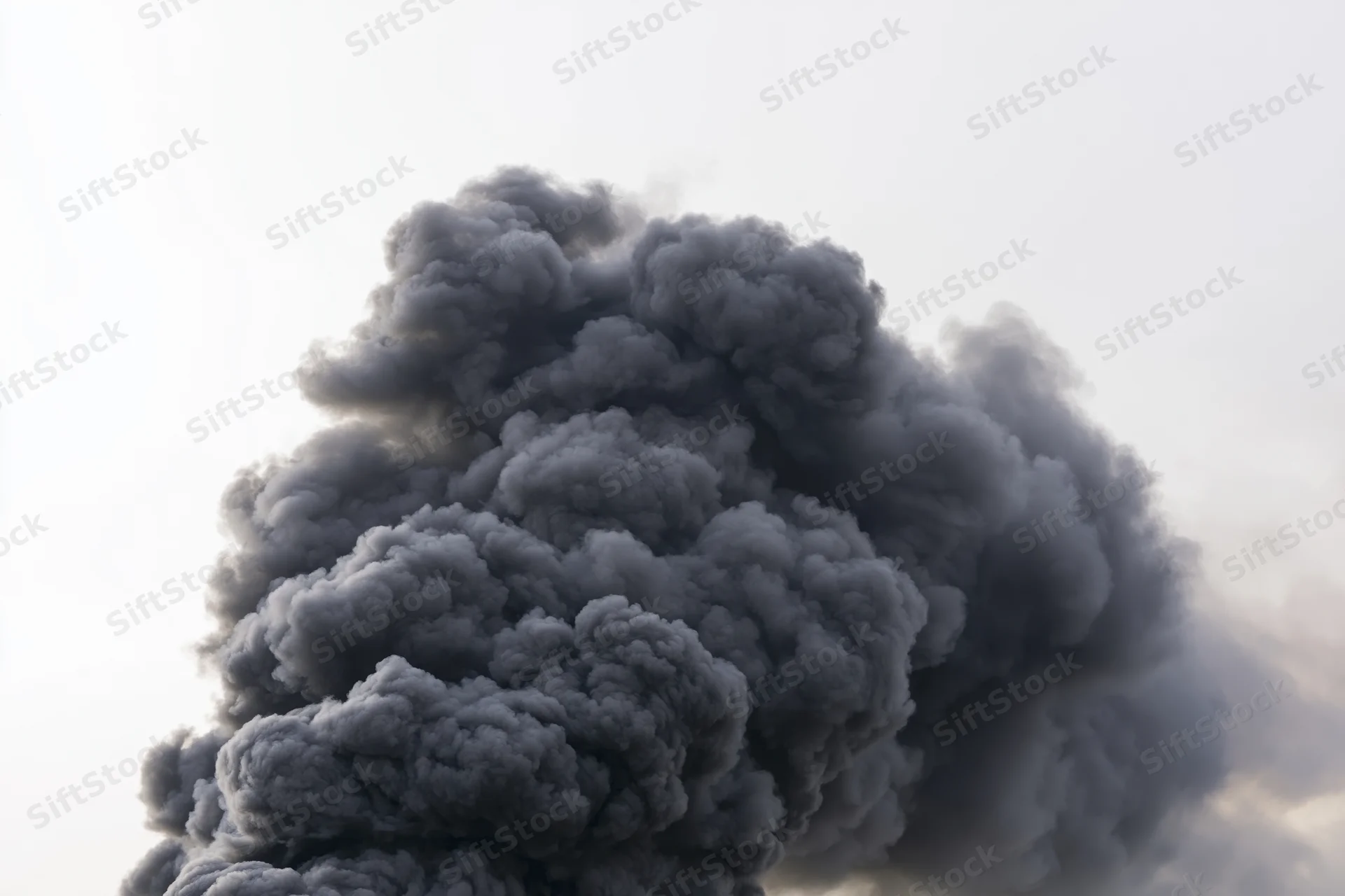 Thick black smoke billowing upward in a dense turbulent column against the sky