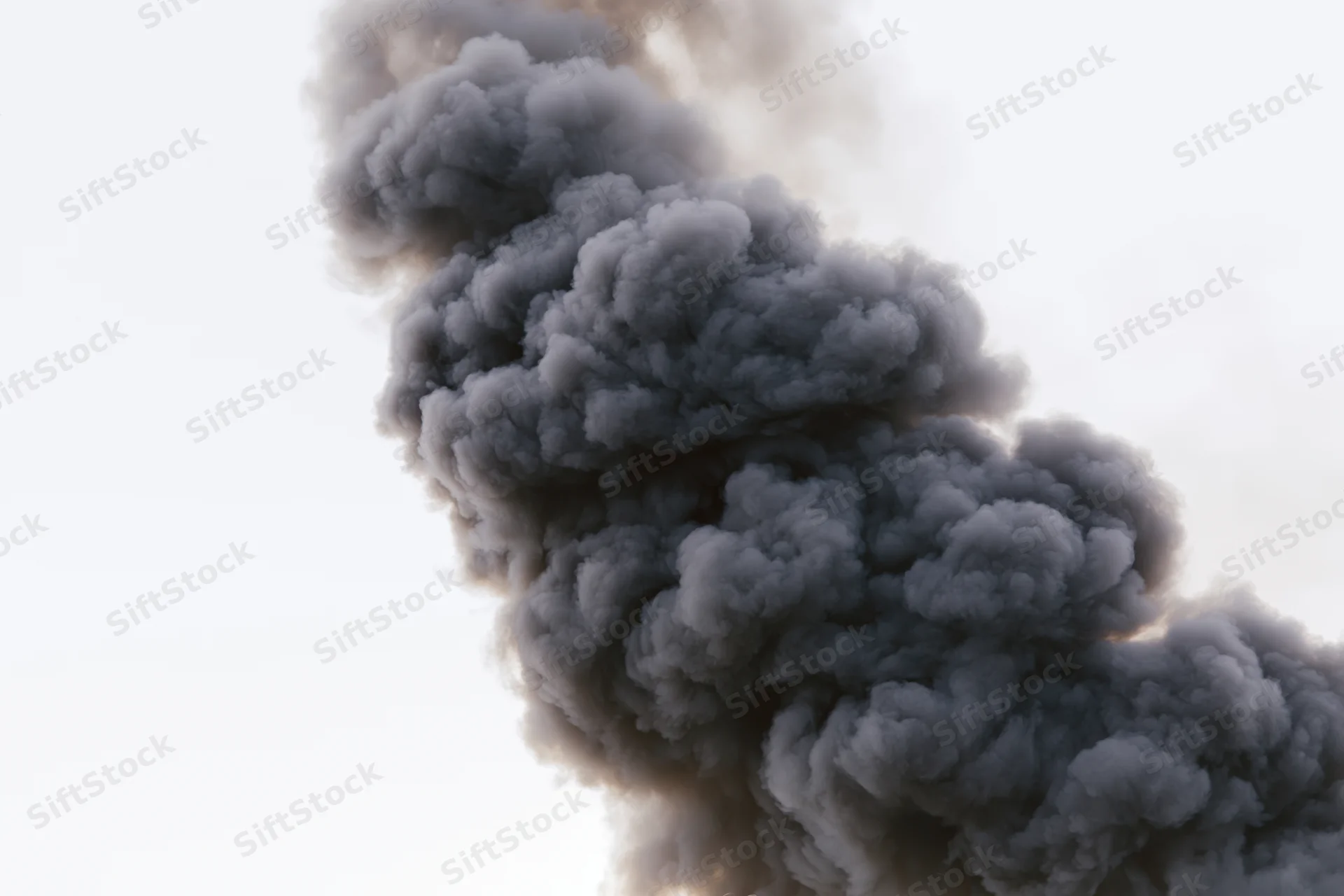 Thick dark smoke rising in a turbulent column against a white sky