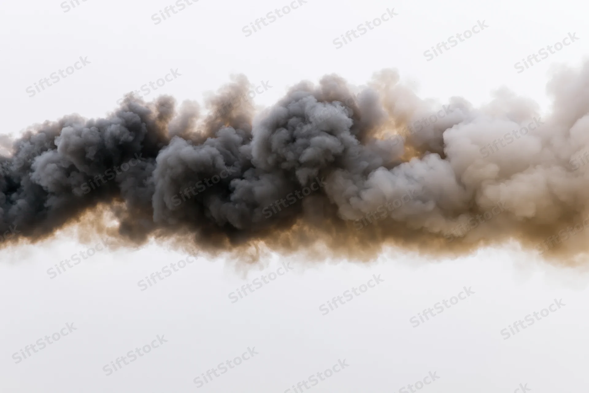 Thick dark smoke plume billowing horizontally across pale sky