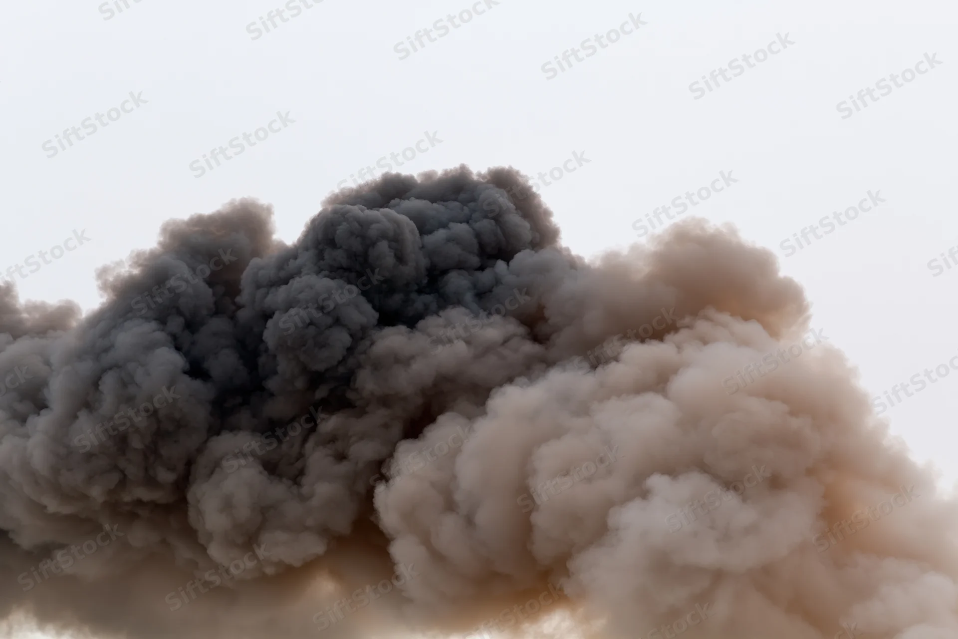 Thick dark smoke billowing horizontally across a pale sky