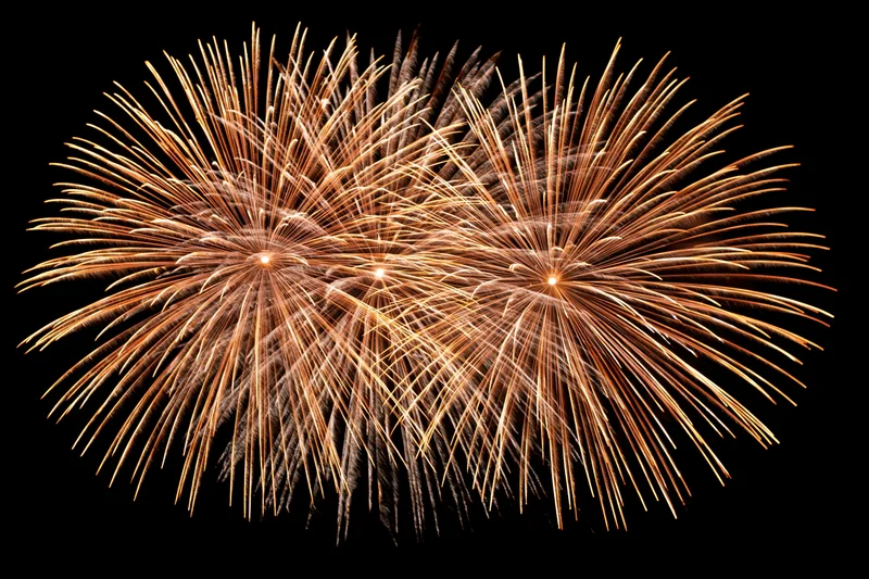 Golden fireworks bursting simultaneously in the night sky