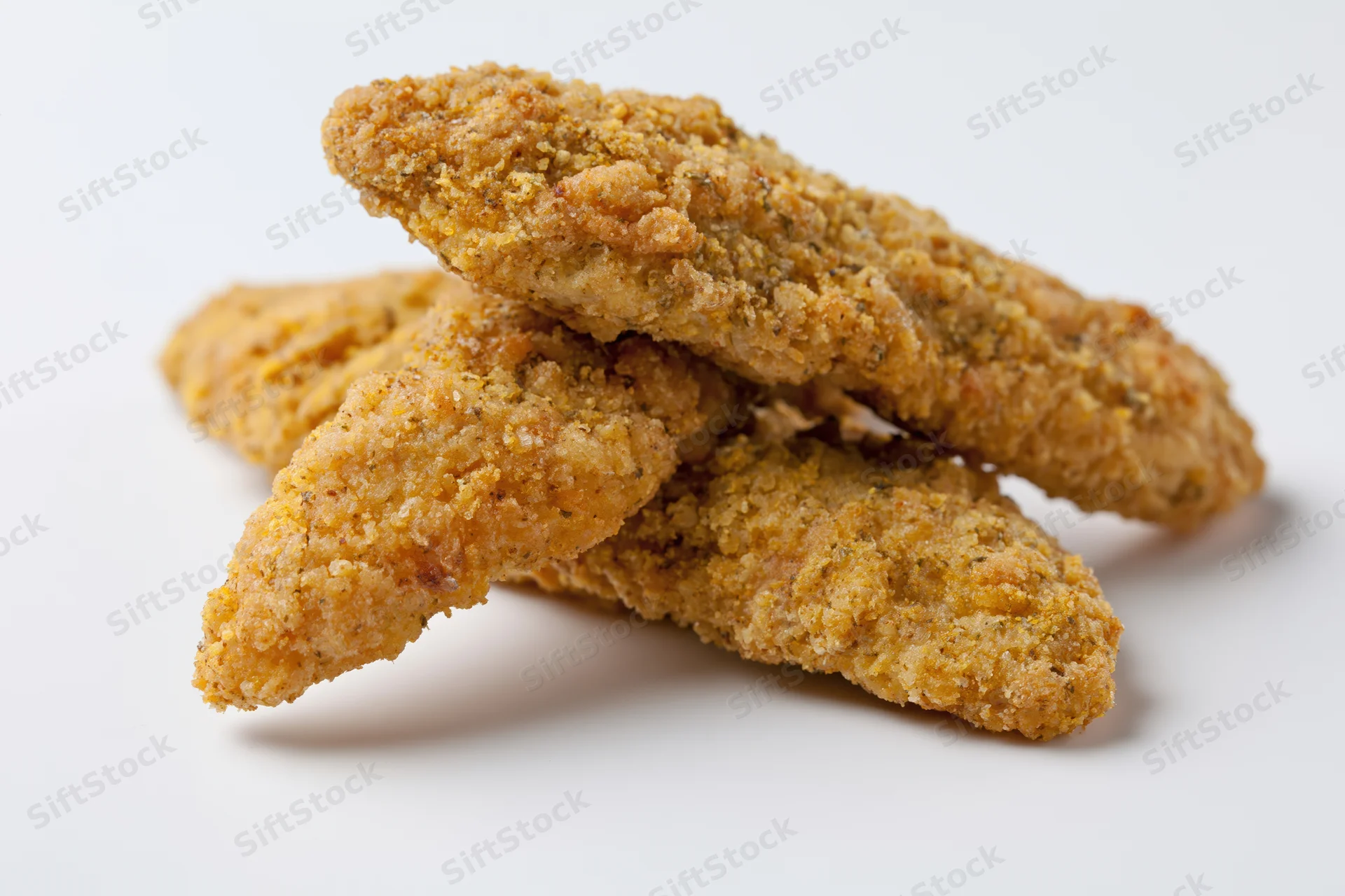Breaded chicken tenders stacked on a white surface
