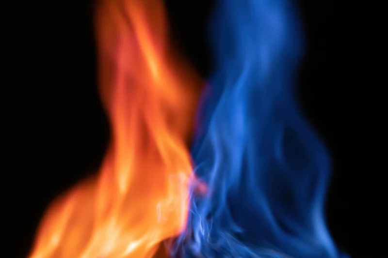 Two opposing columns of orange and blue flame burning against black background