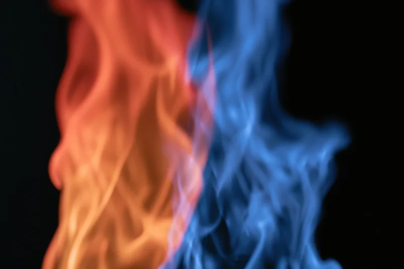 Two opposing columns of orange and blue flame rising against a black background