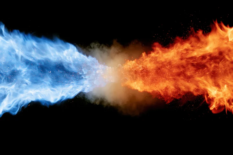Blue and orange flames colliding in mid-air against black background