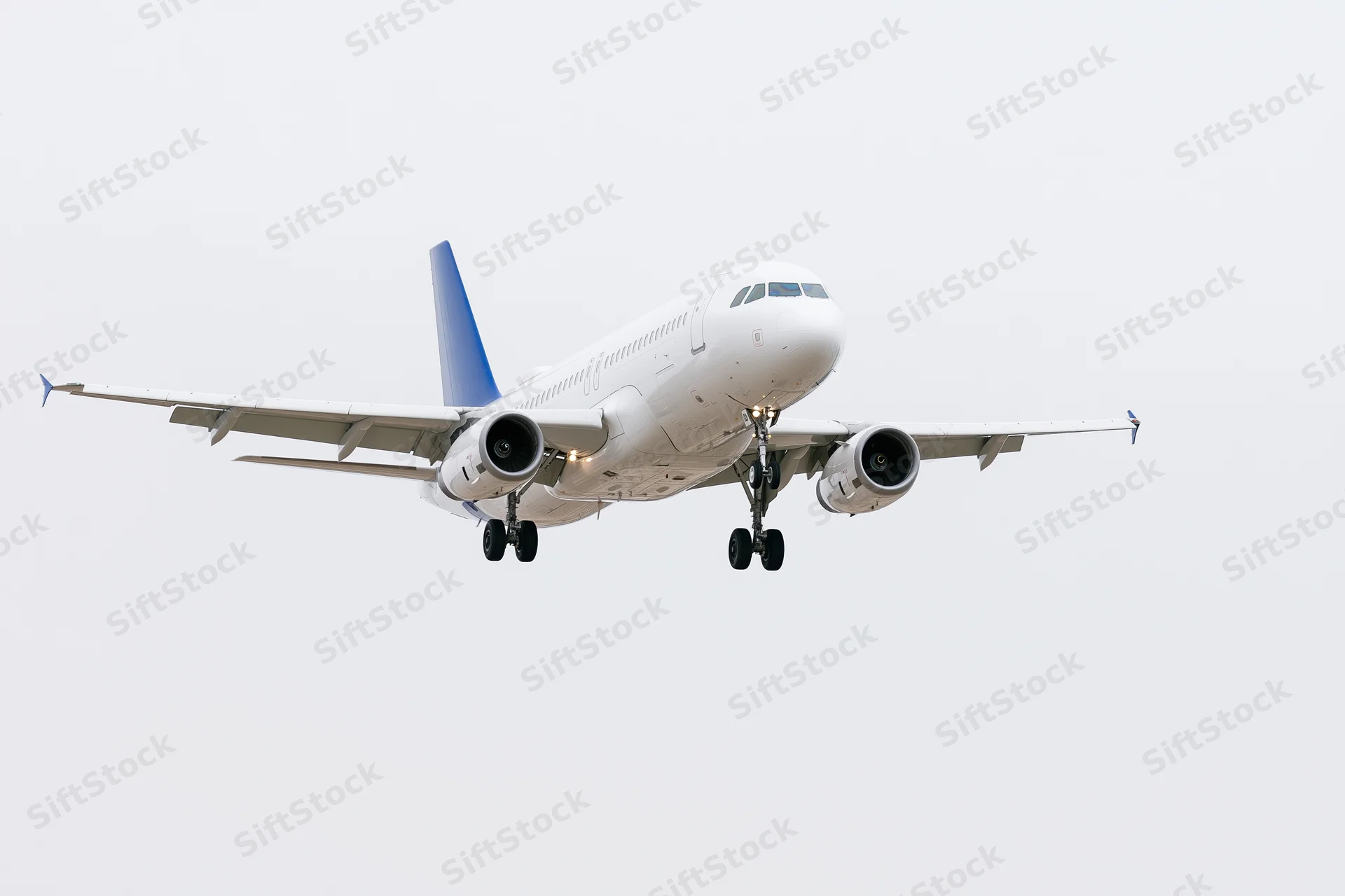 White and blue commercial passenger jet approaching for landing against overcast sky