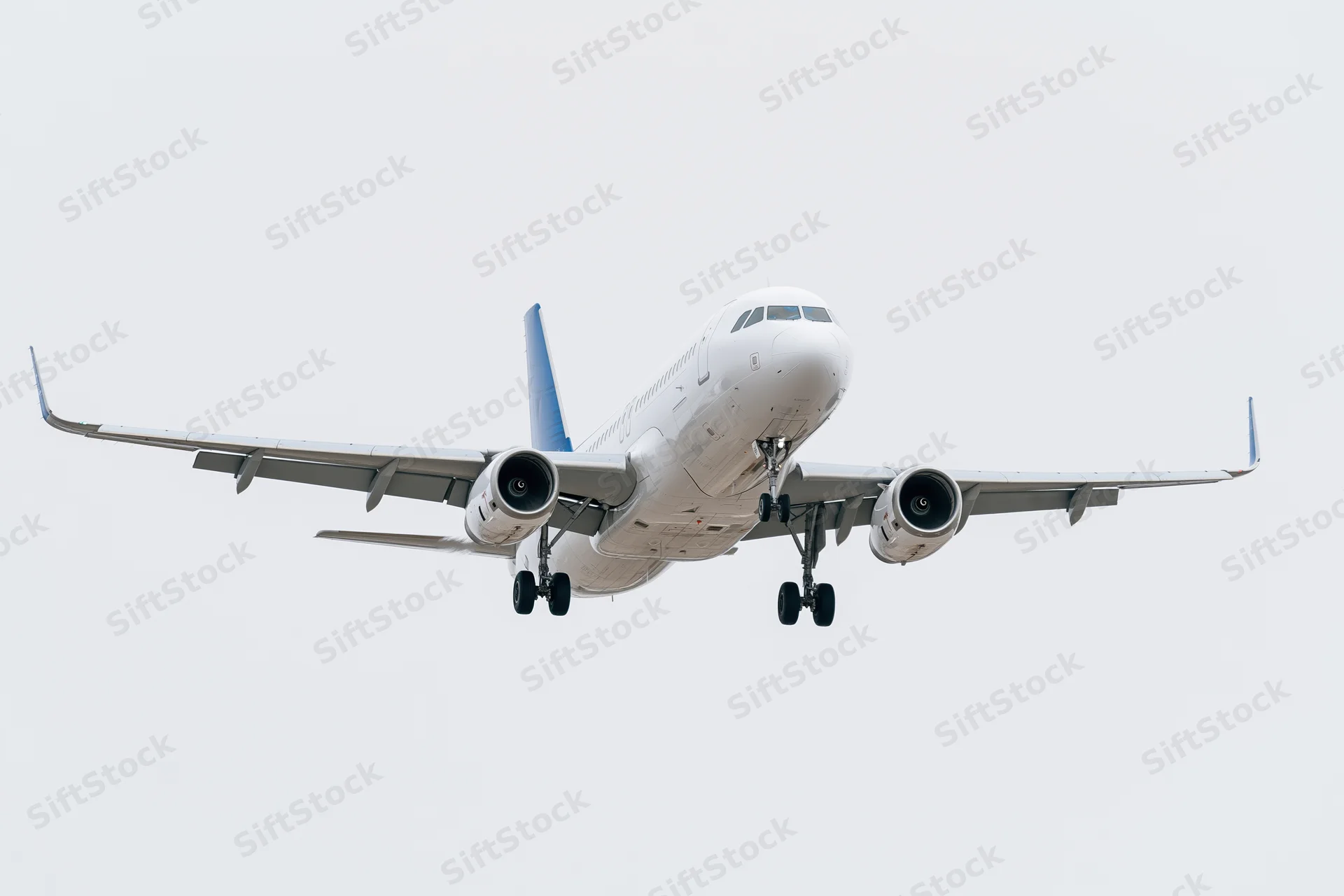 White and blue commercial passenger jet approaching for landing against overcast sky