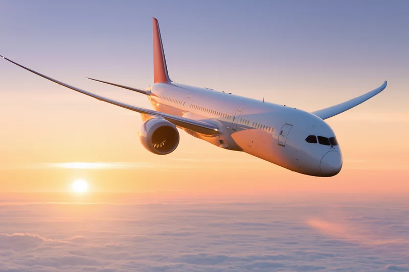 White commercial jet in level flight above clouds at sunset