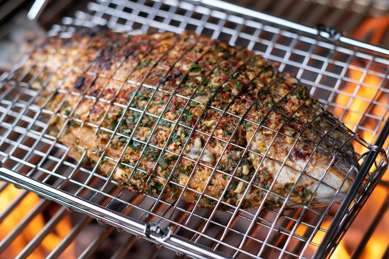 Whole seasoned fish in a wire basket grilling over open flame