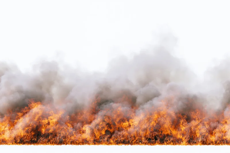 Wide low fire burning horizontally across frame with dense orange flames and rising smoke