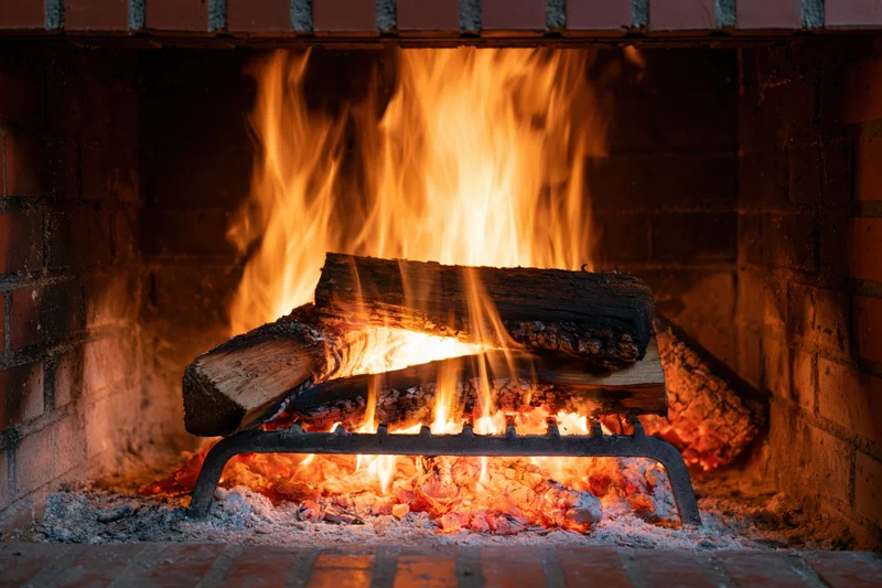 Wood logs burning in a brick fireplace with flames and embers glowing warmly