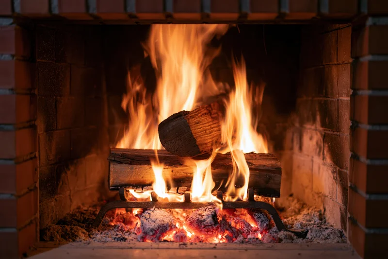 Wood logs burning in a brick fireplace with flames and embers glowing warmly