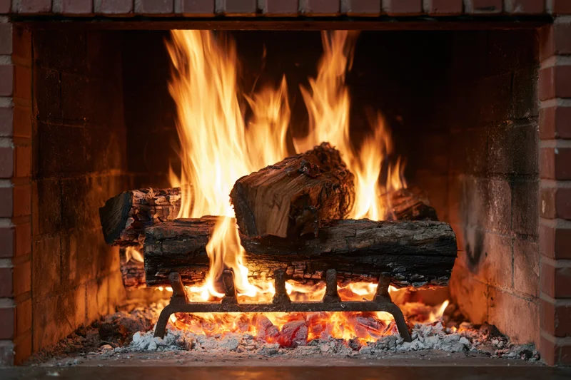 Burning wood logs in a brick fireplace with flames and embers glowing warmly