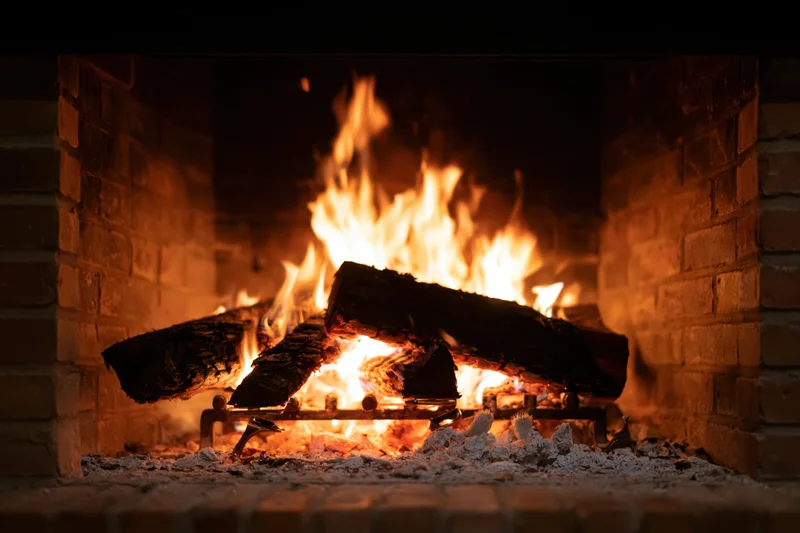Burning wood logs in a brick fireplace at night