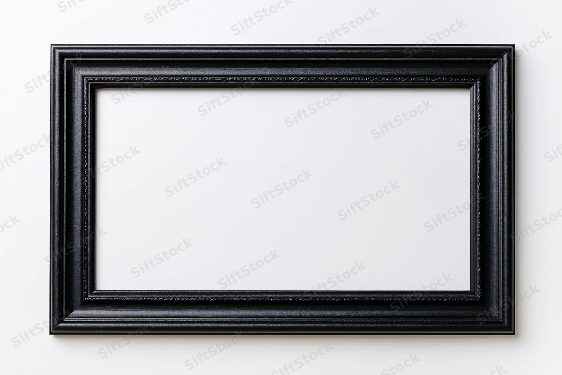 Black rectangular picture frame with ornate molding hanging on a white wall, empty and ready for display