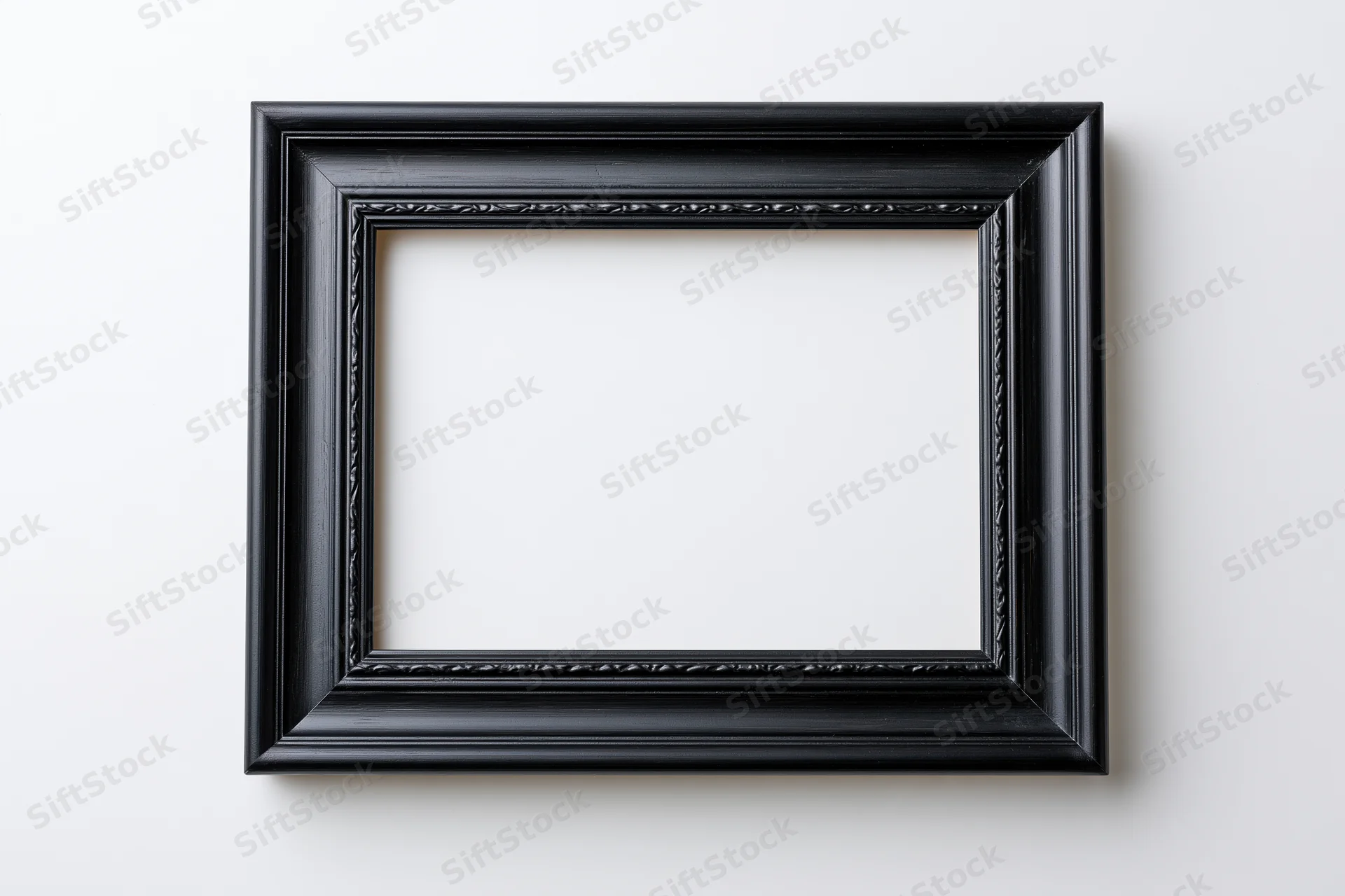 Black rectangular picture frame with molded edges hanging on white wall