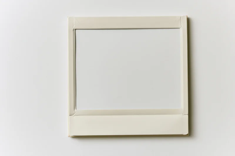 Blank instant film print with white image area lying flat on light surface