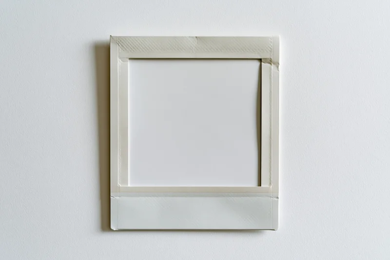 Blank instant film print with white border hanging on a plain wall