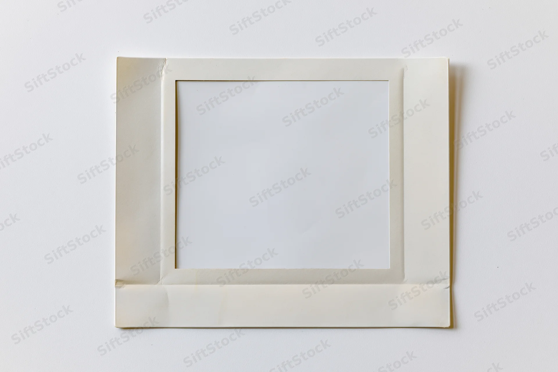Blank instant film print with white image area lying flat on white surface