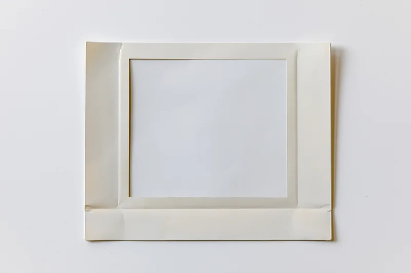 Blank instant film print with white image area lying flat on white surface