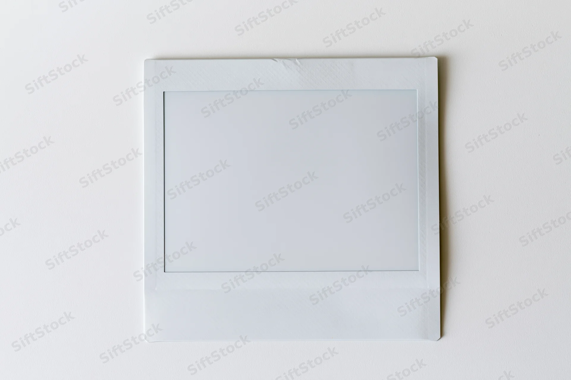 Blank instant film print lying flat on white surface