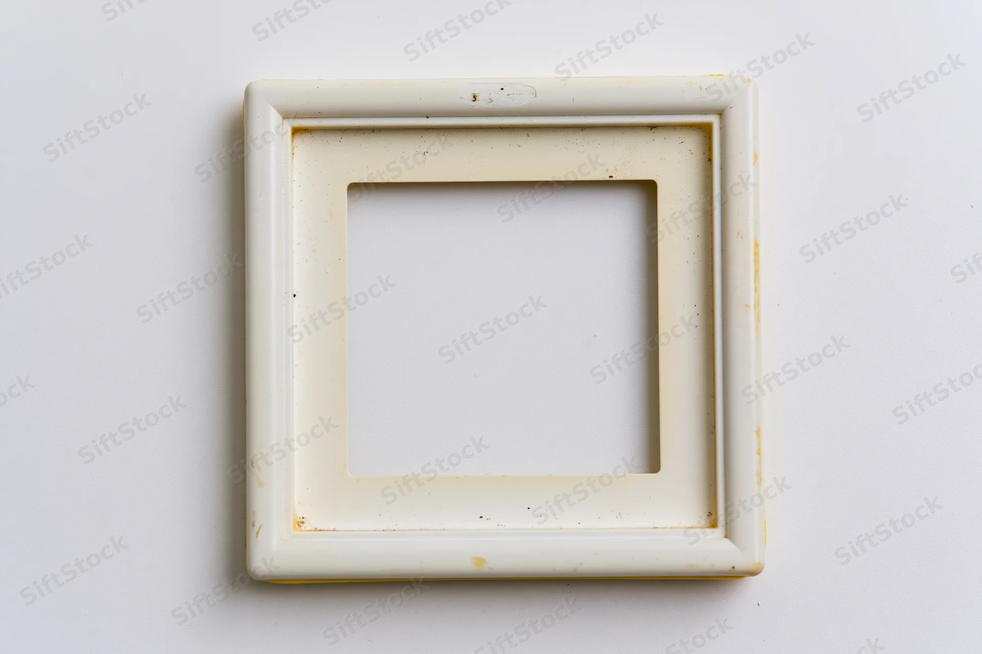 Vintage polaroid photo frame lying flat on white surface with chipped enamel and yellowed edges