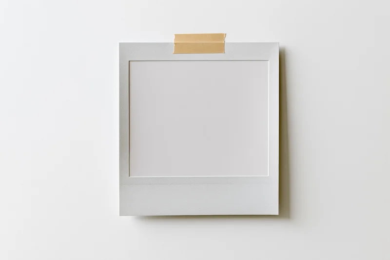 Blank polaroid photo print taped to white surface