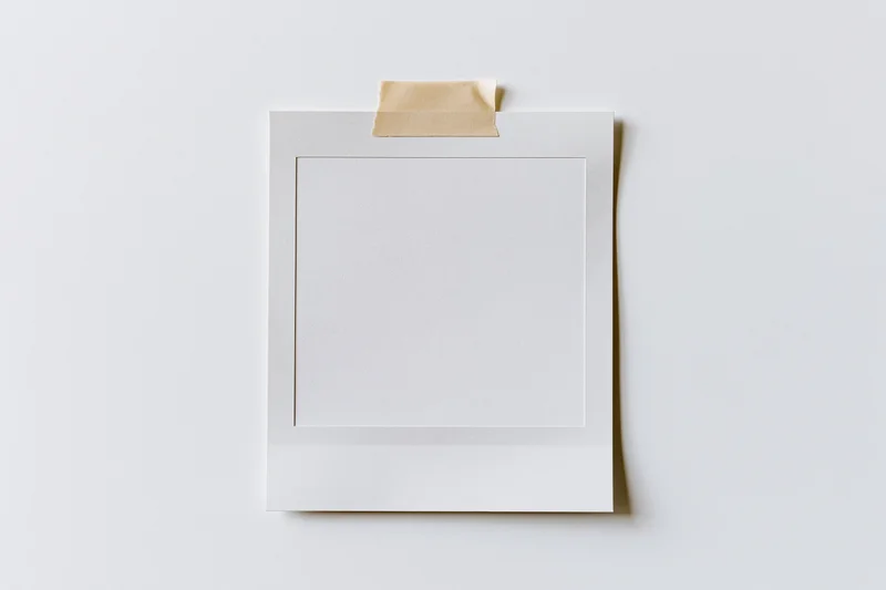 Blank polaroid photo print taped to white surface