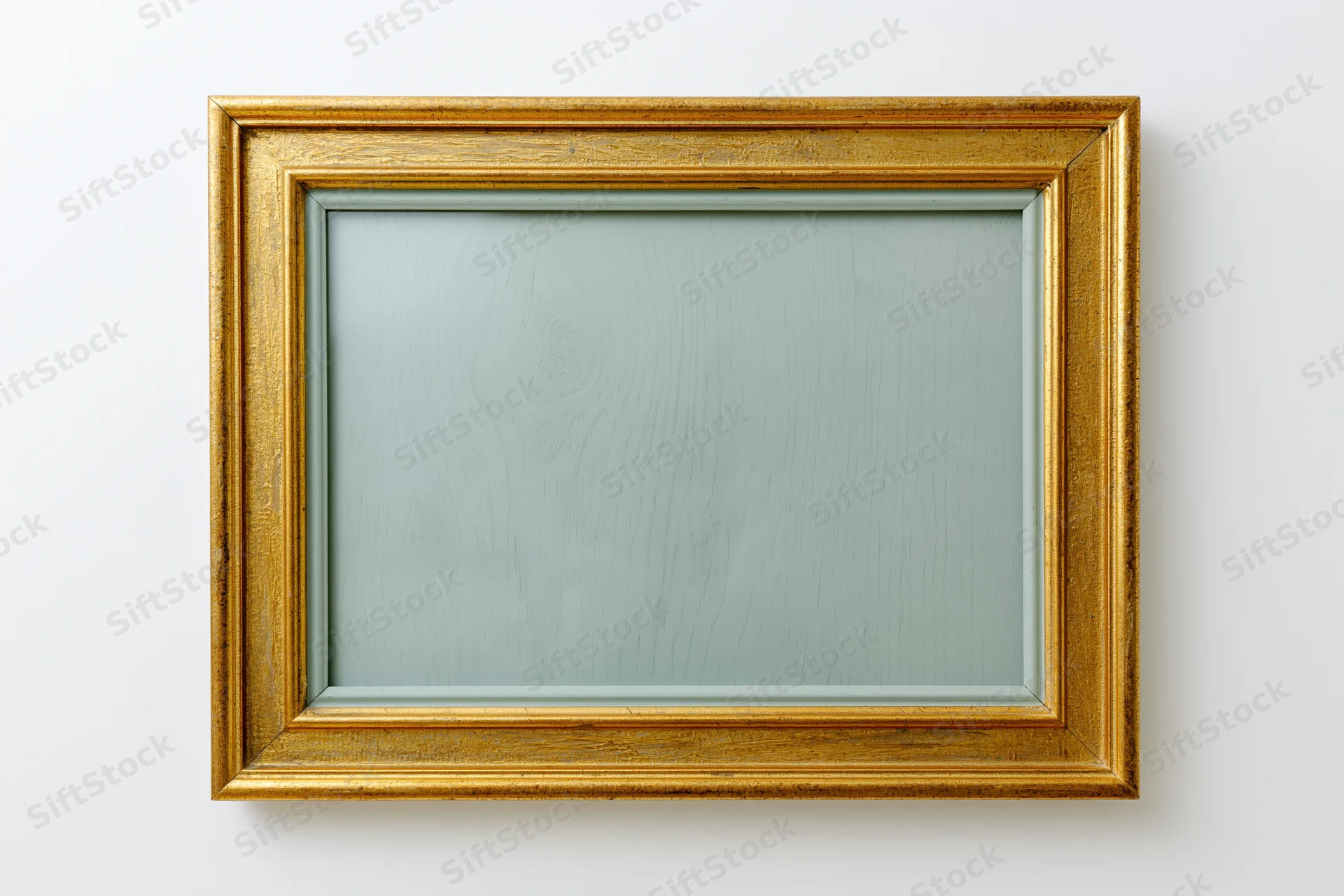 Gold rectangular frame hanging on white wall with empty glass front