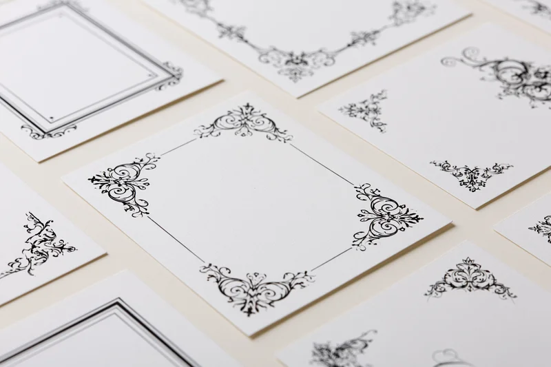 Ornate victorian-style decorative frames on white cards arranged in flat lay on cream surface