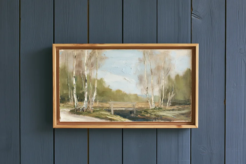 Framed oil painting of birch trees and a forest landscape hanging on a dark grey wooden wall