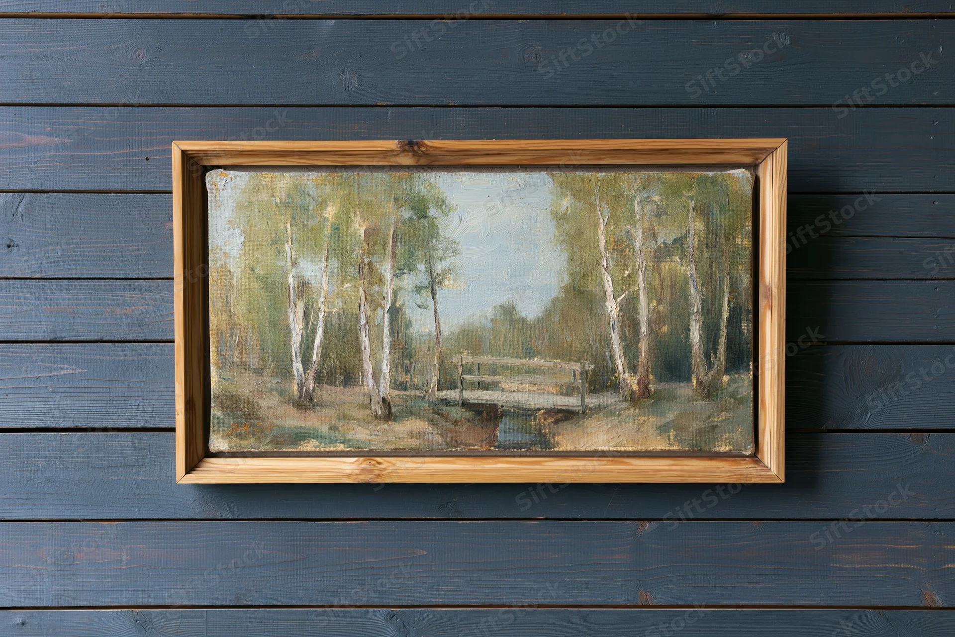 Framed oil painting of birch trees and a bridge in a forest landscape hanging on a dark grey wooden wall