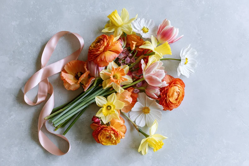 Loose bouquet of mixed spring flowers with ribbon on concrete surface