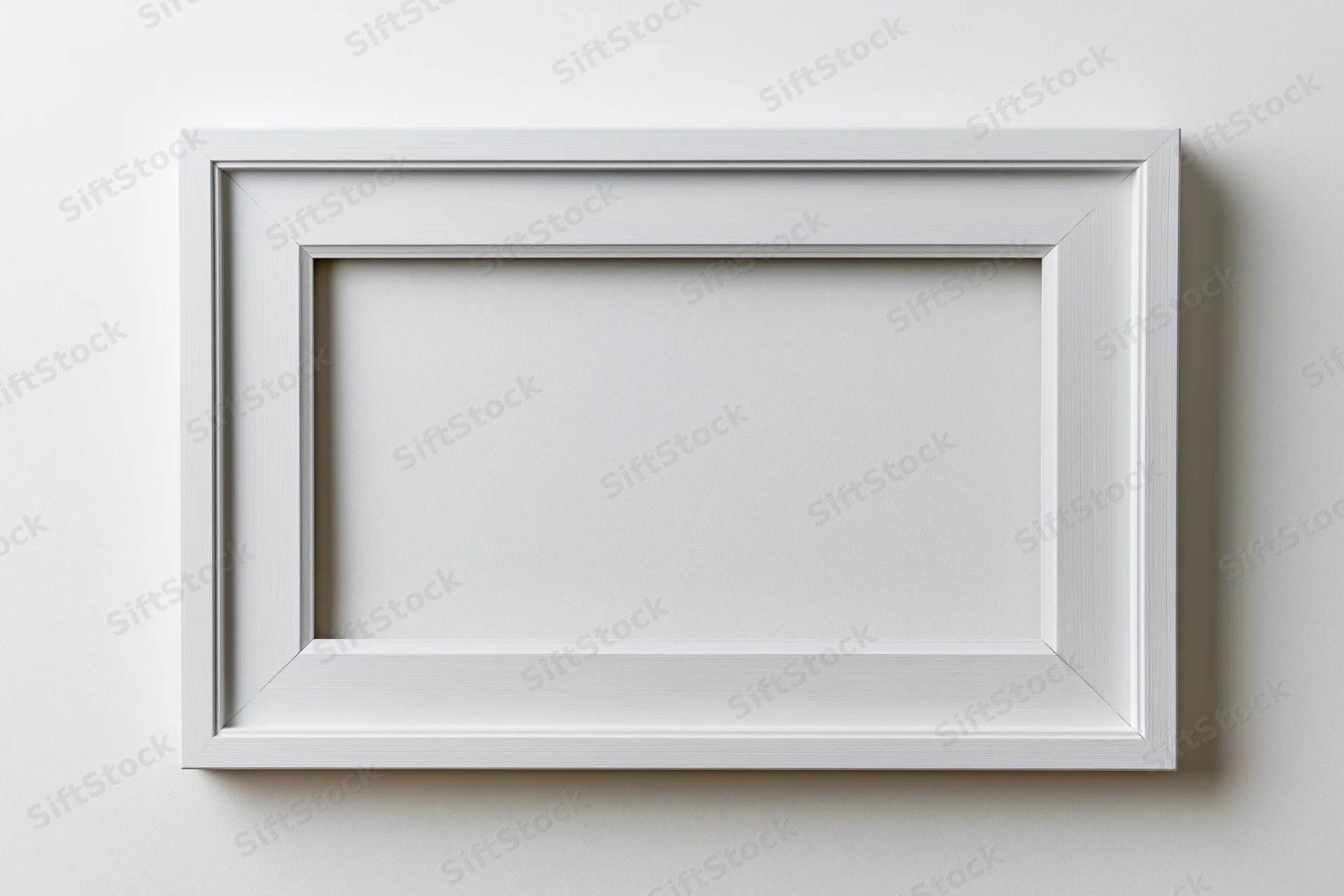 White wooden picture frame hanging on a plain wall with empty center for display
