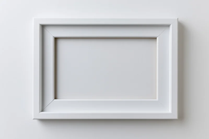 White wooden picture frame hanging on a plain wall with empty center for display