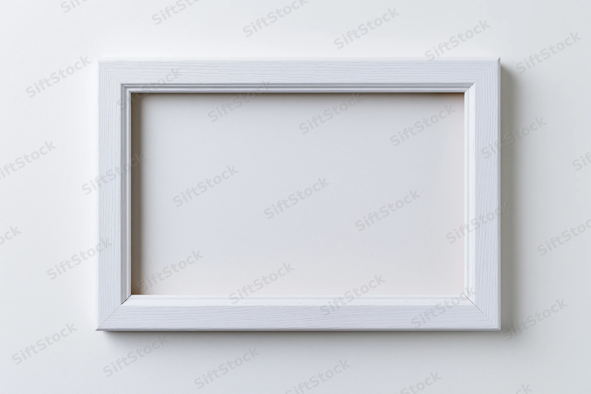 White rectangular picture frame mounted on a plain wall with empty interior space