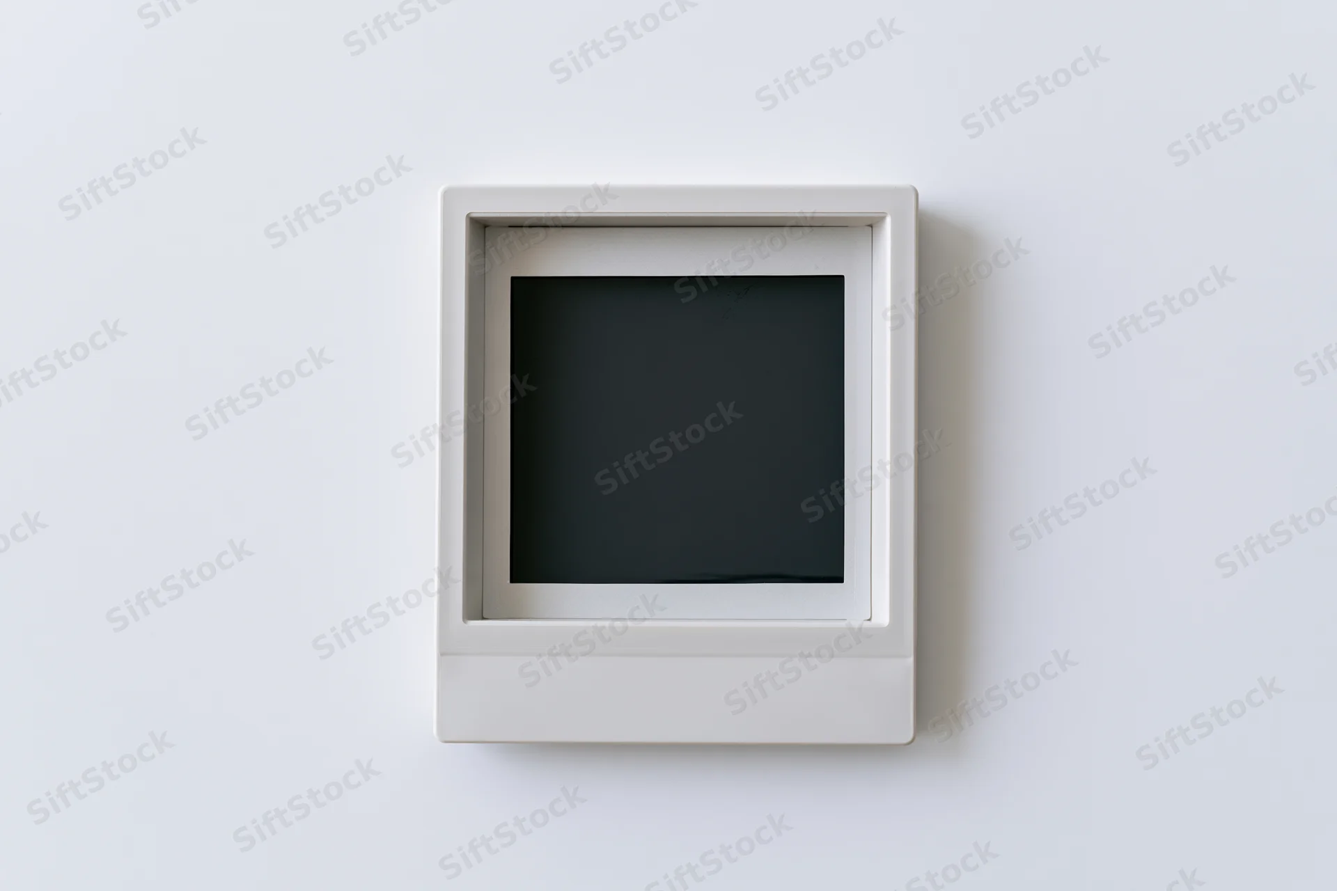 Blank polaroid instant photo print mounted flat on white wall center