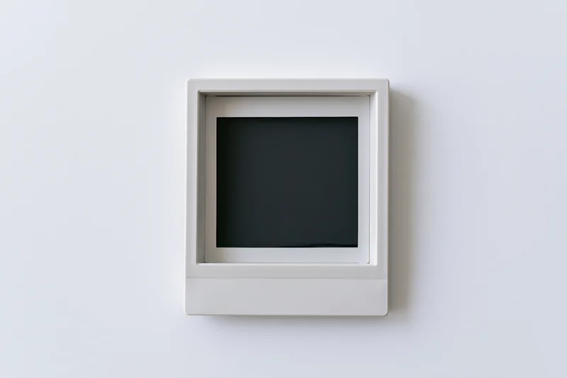 Blank polaroid instant photo print mounted flat on white wall center