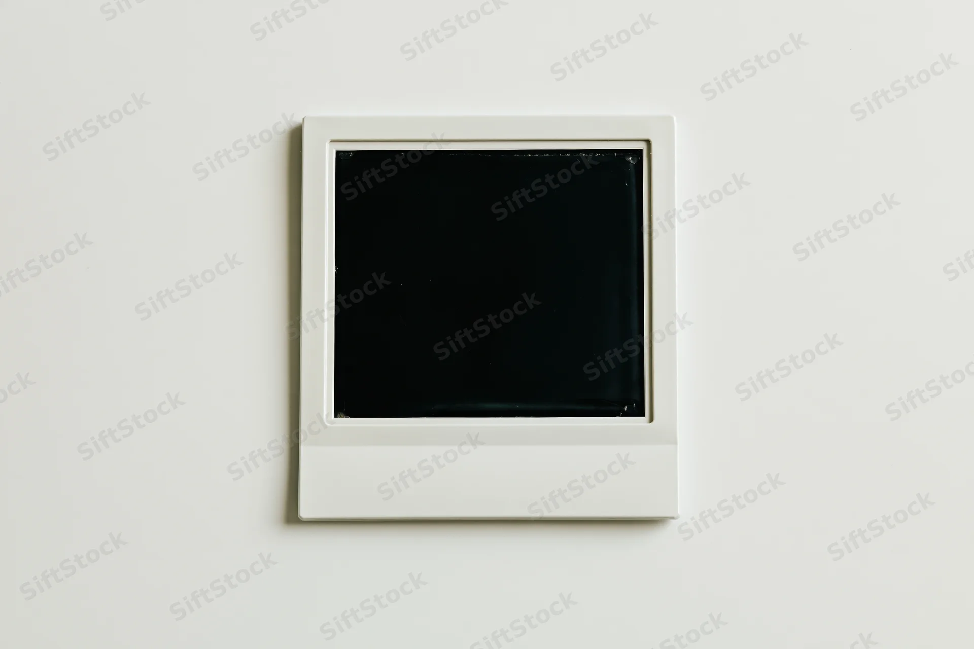 Blank polaroid instant photo print lying flat center on white surface