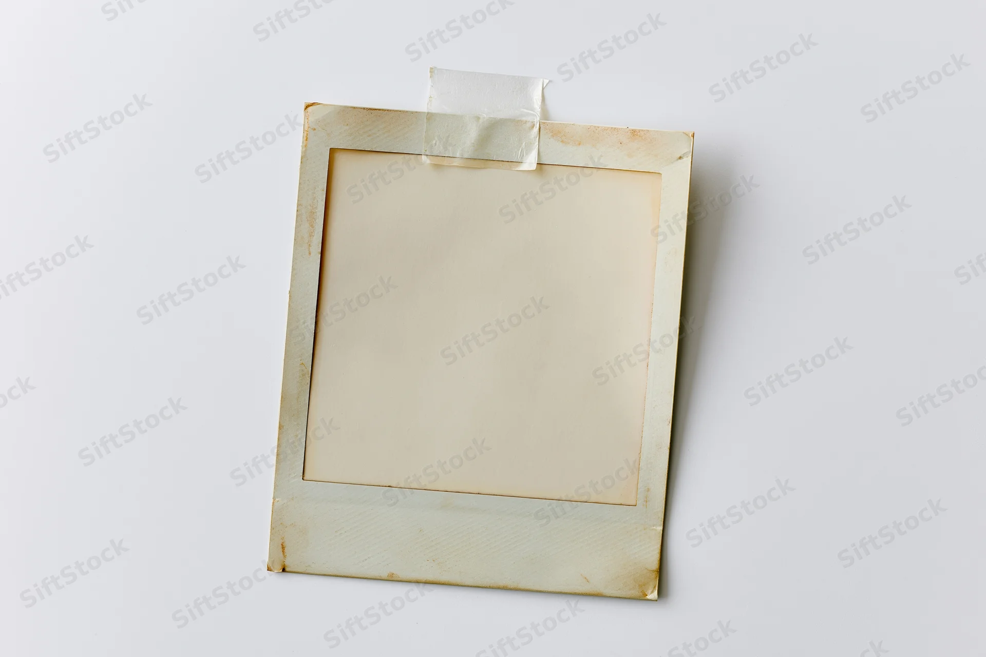 Blank instant film photo print taped to white surface