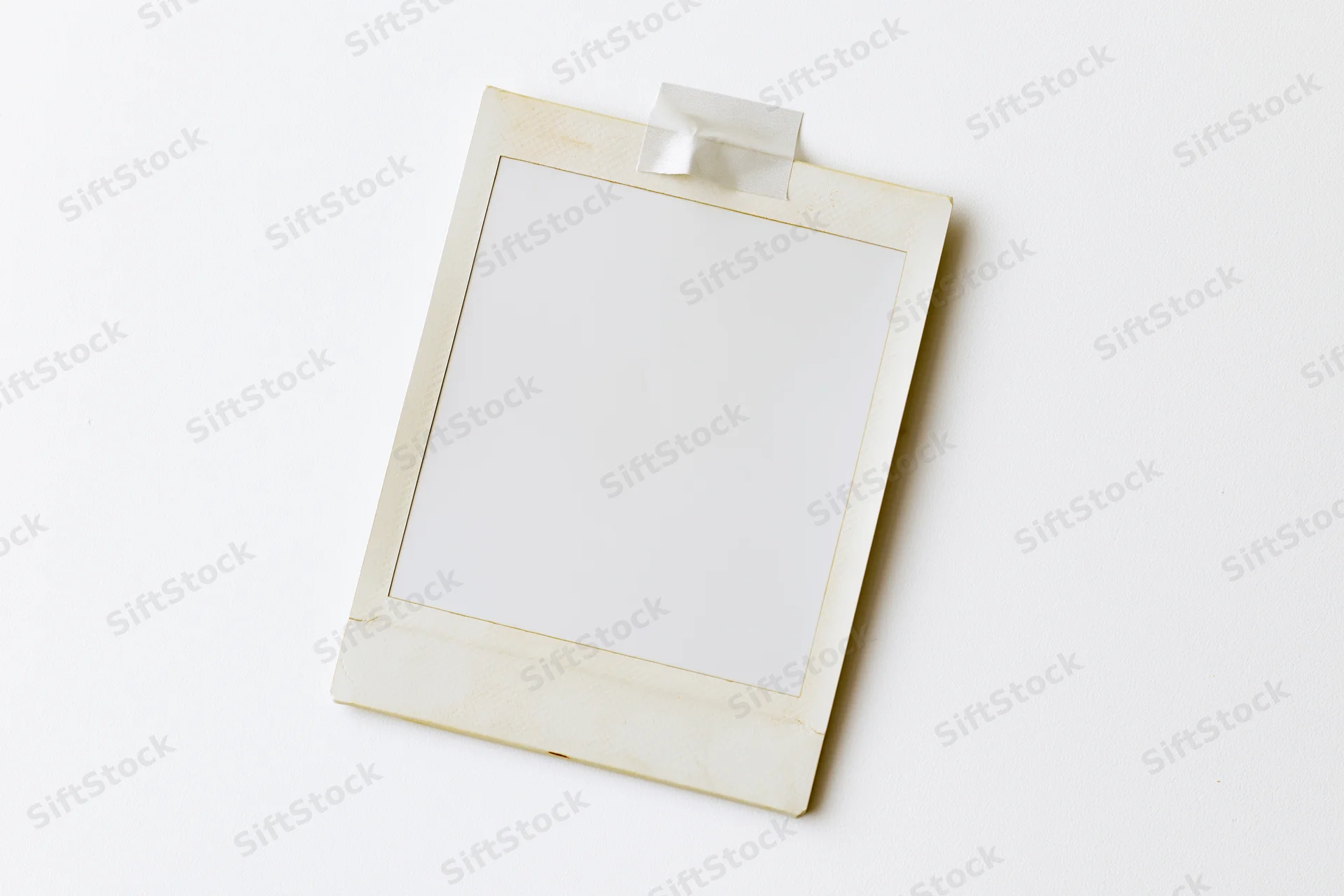Blank instant photo print taped to white surface