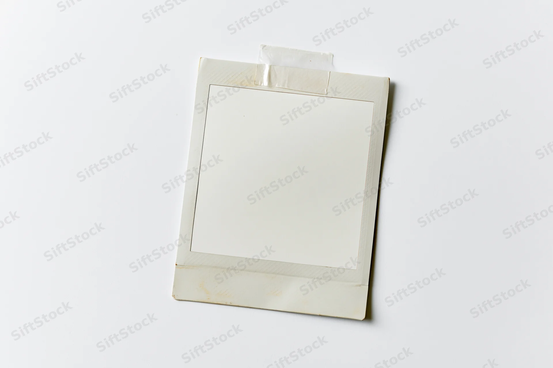 Blank instant film photo print taped to white surface