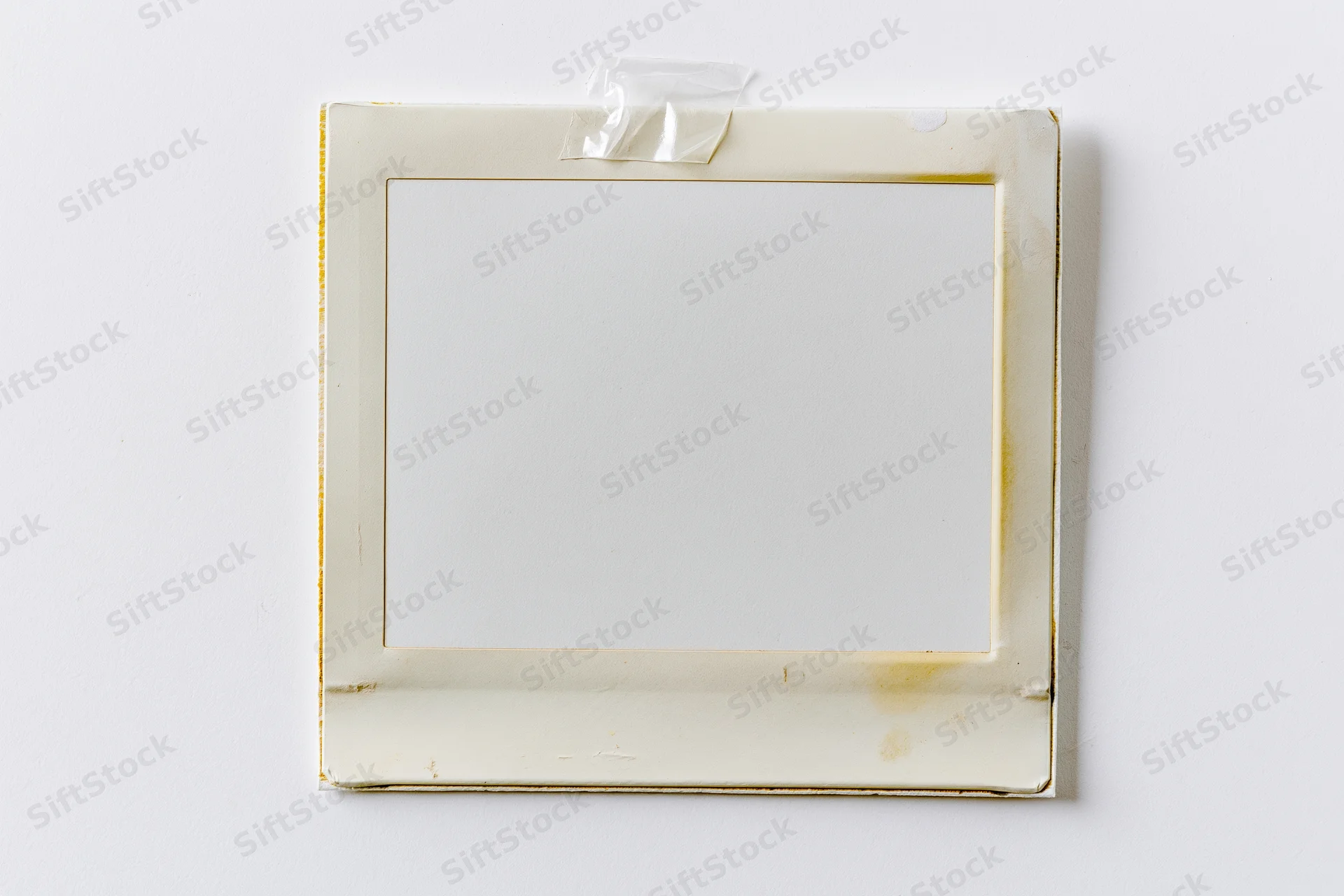 Blank instant film photo print taped to white surface