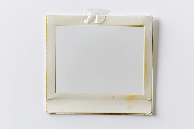 Blank instant film photo print taped to white surface