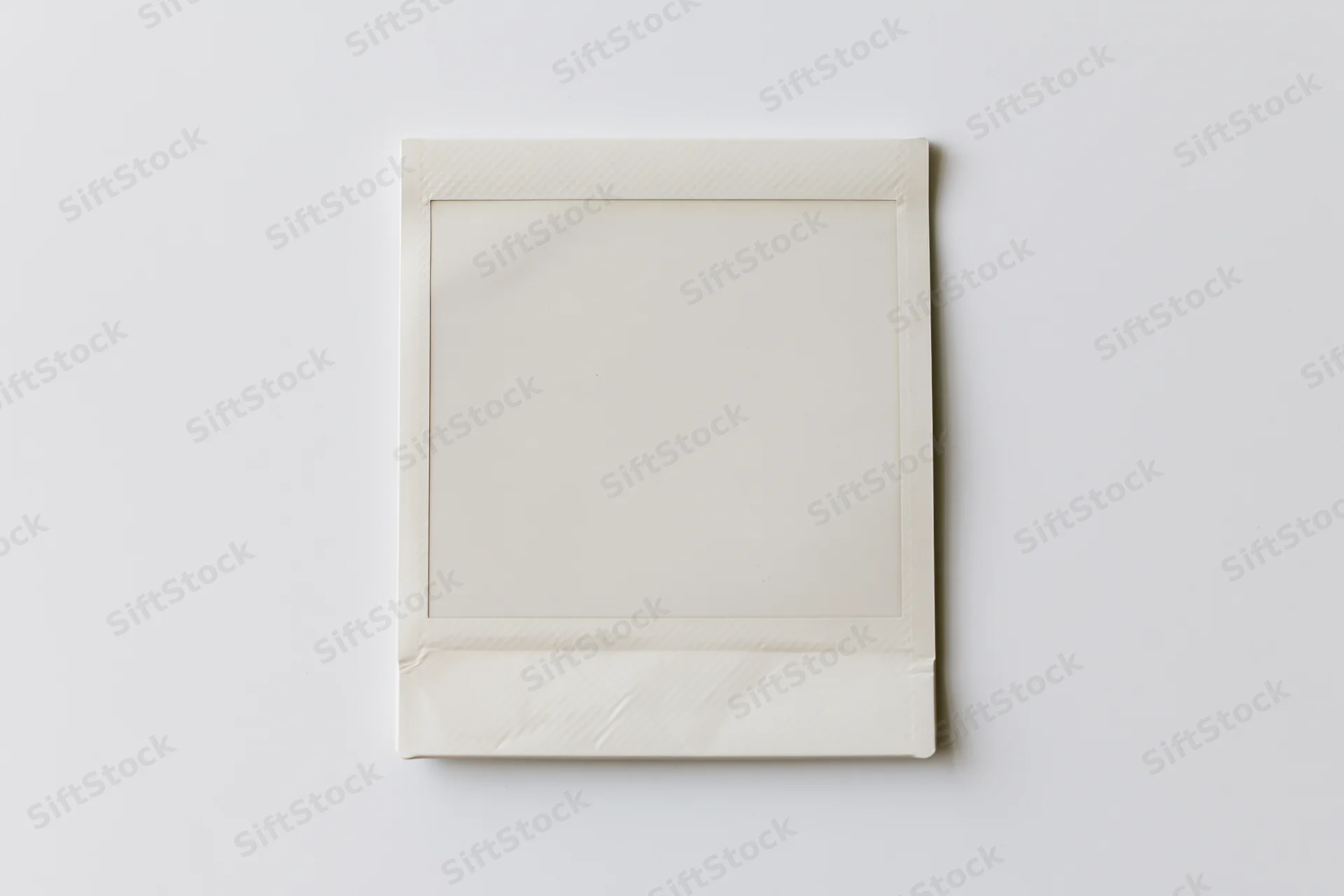 Blank instant photo print lying flat centered on white surface