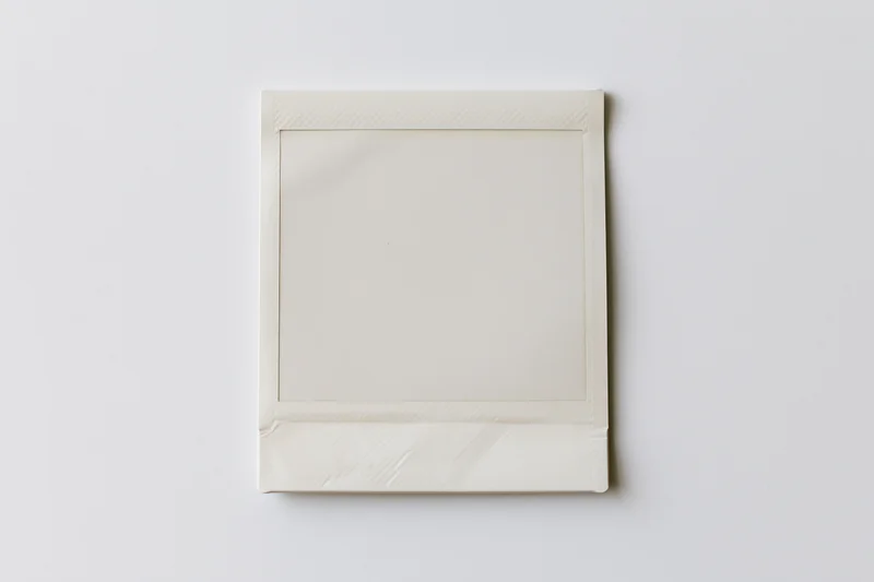 Blank instant photo print lying flat centered on white surface