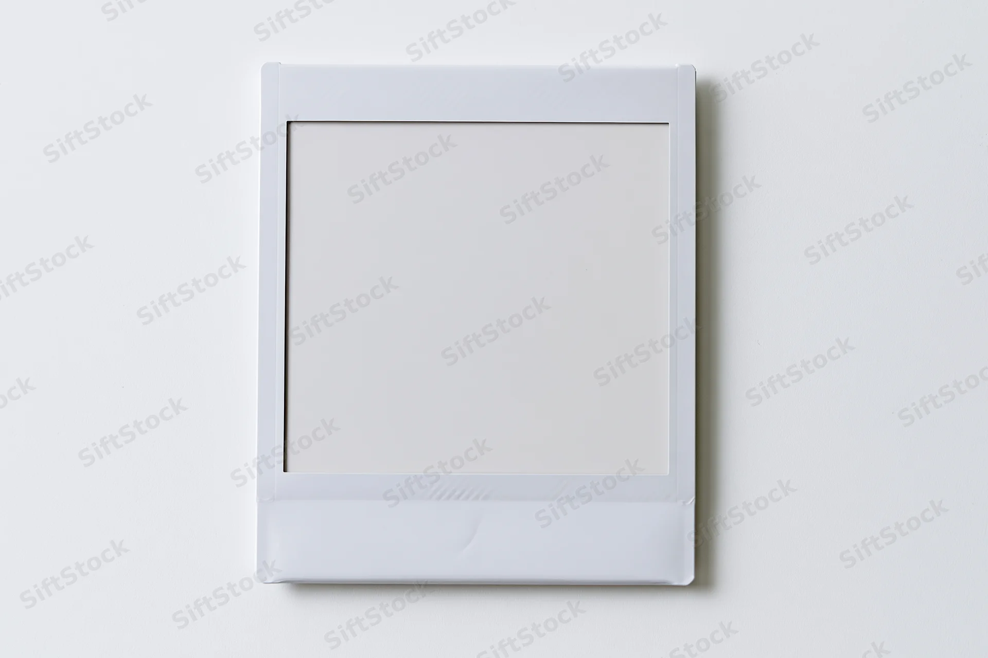 Blank instant photo print lying flat centered on white surface