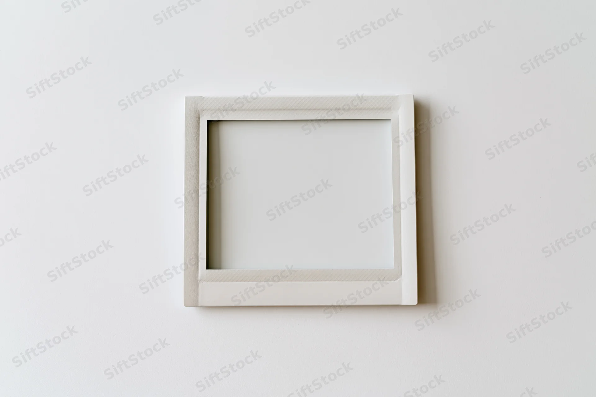 White square frame hanging on a plain wall with blank interior space